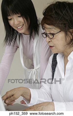 Close-up of a senior woman using a laptop with her granddaughter sitting beside her View Large Photo Image Stock Photo - Close-up of a senior woman using a laptop with her granddaughter sitting beside her. Fotosearch