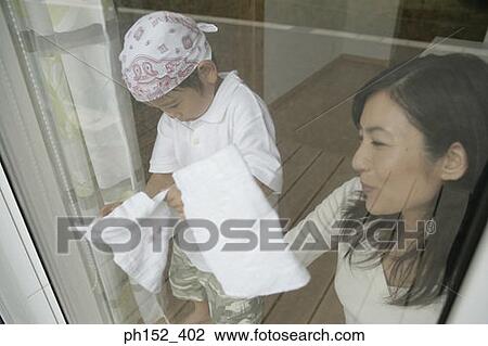 Close-up of a young woman cleaning a window with her son standing beside her View Large Photo Image Stock Image - Close-up of a young woman cleaning a window with her son standing beside her. Fotosearch