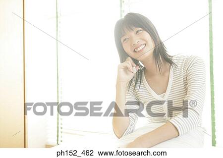 Close-up of a young woman talking on a mobile phone and smiling View Large Photo Image Stock Image - Close-up of a young woman talking on a mobile phone and smiling. Fotosearch