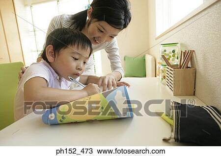 Stock Image - Close-up of a young woman teaching her brother. Fotosearch