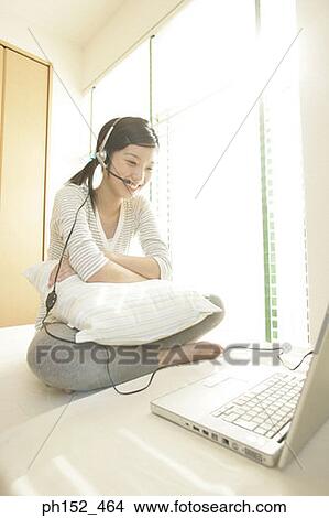 Close-up of a young woman wearing a headset and sitting in front of a laptop View Large Photo Image Picture - Close-up of a young woman wearing a headset and sitting in front of a laptop. Fotosearch