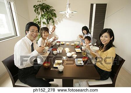 Stock Photo - Family sitting around the dining table. Fotosearch