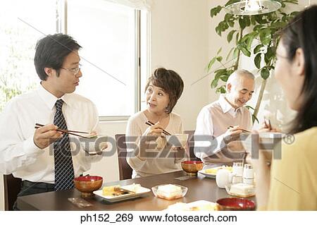 Stock Photo - Family sitting at the dining table. Fotosearch