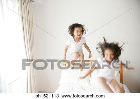 Girl and her sister jumping on the bed View Large Photo Image Stock Image - Girl and her sister jumping on the bed. Fotosearch