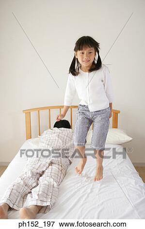Girl jumping on the bed with her father sleeping beside her View Large Photo Image Stock Photo - Girl jumping on the bed with her father sleeping beside her. Fotosearch