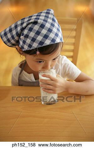 Stock Photo - Girl sitting at the table and drinking milk. Fotosearch