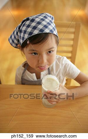 Stock Photo - Girl sitting at the table and drinking milk. Fotosearch