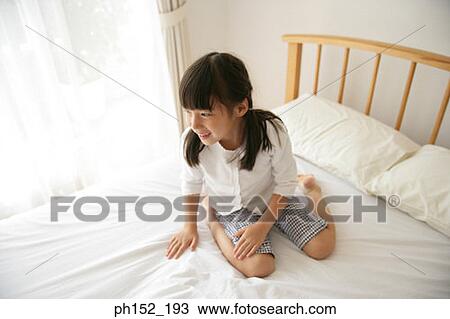 Stock Image - Girl sitting on the bed and smiling. Fotosearch