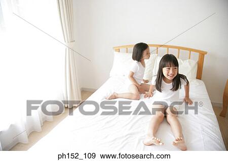 Girl sitting with her sister on the bed View Large Photo Image Stock Photo - Girl sitting with her sister on the bed. Fotosearch