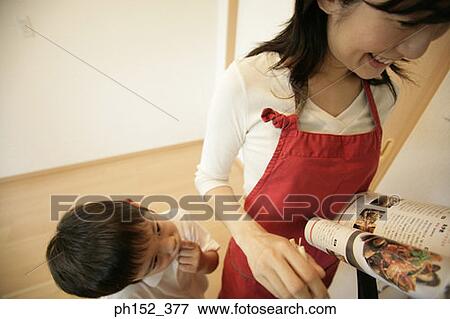 High angle view of a boy standing beside his mother and cooking with the help of a recipe book View Large Photo Image Stock Photo - High angle view of a boy standing beside his mother and cooking with the help of a recipe book. Fotosearch