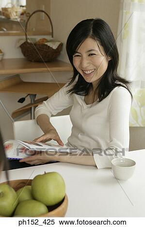 High angle view of a mid adult woman holding a magazine and smiling View Large Photo Image Stock Photography - High angle view of a mid adult woman holding a magazine and smiling. Fotosearch