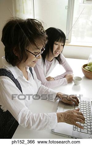 High angle view of a senior woman using a laptop with her granddaughter sitting beside her View Large Photo Image Stock Photograph - High angle view of a senior woman using a laptop with her granddaughter sitting beside her. Fotosearch