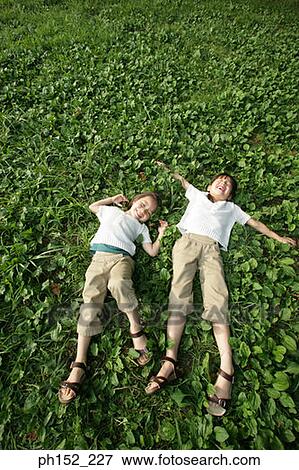 Stock Photo - High angle view of two girls lying in a park. Fotosearch