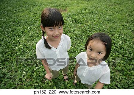 High angle view of two girls standing in a park View Large Photo Image Stock Image - High angle view of two girls standing in a park. Fotosearch