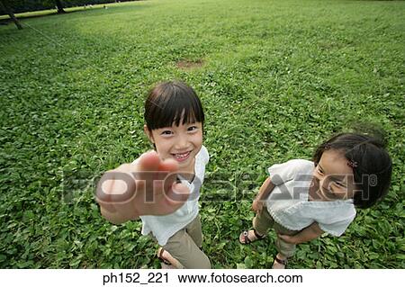 High angle view of two girls standing in a park View Large Photo Image Stock Image - High angle view of two girls standing in a park. Fotosearch