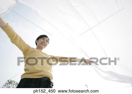 Low angle view of a mid adult woman waving a sheet and smiling View Large Photo Image Stock Image - Low angle view of a mid adult woman waving a sheet and smiling. Fotosearch