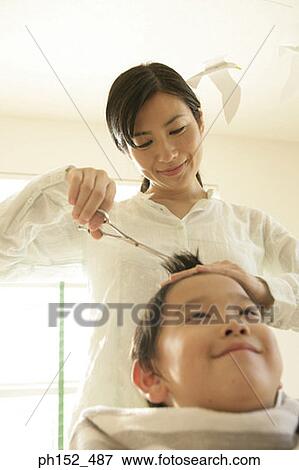 Low angle view of a mid adult woman cutting her son's hair View Large Photo Image Stock Photo - Low angle view of a mid adult woman cutting her son's hair. Fotosearch