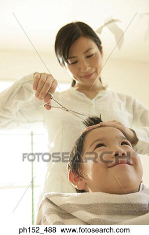 Low angle view of a mid adult woman cutting her son's hair View Large Photo Image Stock Photo - Low angle view of a mid adult woman cutting her son's hair. Fotosearch