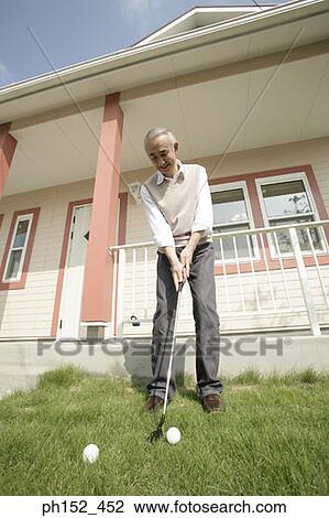 Low angle view of a senior man playing golf in front of a house View Large Photo Image Stock Image - Low angle view of a senior man playing golf in front of a house. Fotosearch