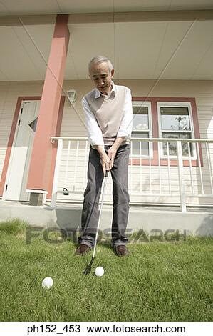 Low angle view of a senior man playing golf in front of a house View Large Photo Image Stock Image - Low angle view of a senior man playing golf in front of a house. Fotosearch
