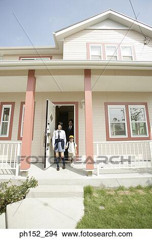 Picture - Mature man stepping out of the house with his son and daughter. Fotosearch