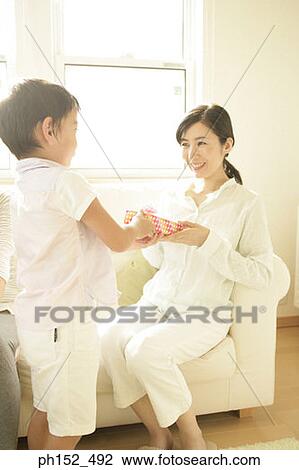 Stock Image - Mature woman taking a gift from her son and smiling. Fotosearch