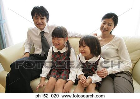 Mid adult couple and their daughters sitting on a couch and smiling View Large Photo Image Stock Image - Mid adult couple and their daughters sitting on a couch and smiling. Fotosearch