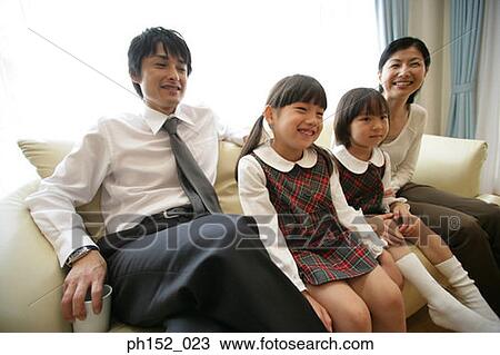 Mid adult couple and their daughters sitting on a couch and smiling View Large Photo Image Stock Image - Mid adult couple and their daughters sitting on a couch and smiling. Fotosearch