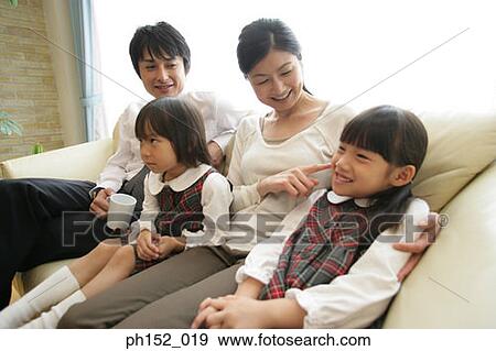 Mid adult couple and their daughters sitting on a couch View Large Photo Image Stock Photo - Mid adult couple and their daughters sitting on a couch. Fotosearch