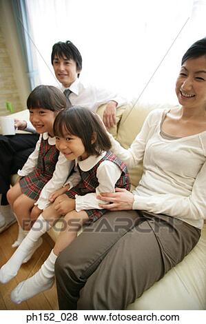 Mid adult couple and their daughters sitting on a couch and smiling View Large Photo Image Stock Photo - Mid adult couple and their daughters sitting on a couch and smiling. Fotosearch