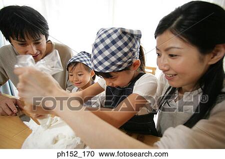 Mid adult couple and their two daughters sitting at the table and decorating a cake View Large Photo Image Stock Image - Mid adult couple and their two daughters sitting at the table and decorating a cake. Fotosearch