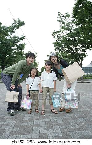 Mid adult couple and their two daughters holding shopping bags View Large Photo Image Stock Image - Mid adult couple and their two daughters holding shopping bags. Fotosearch