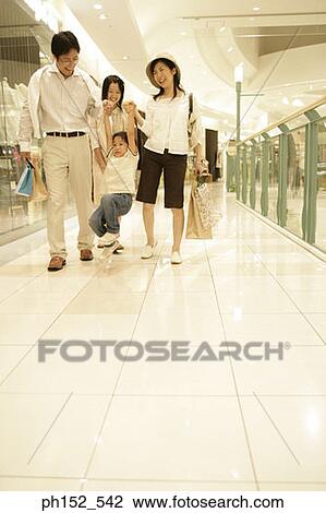 Mid adult couple carrying their son with their daughter behind them in a shopping mall View Large Photo Image Stock Image - Mid adult couple carrying their son with their daughter behind them in a shopping mall. Fotosearch
