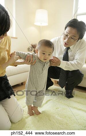 Mid adult couple helping their baby boy stand View Large Photo Image Picture - Mid adult couple helping their baby boy stand. Fotosearch