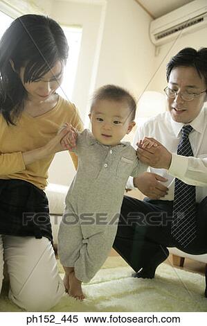 Stock Photography - Mid adult couple helping their baby boy stand. Fotosearch