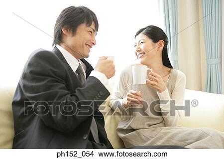 Picture - Mid adult couple holding cups of coffee and smiling. Fotosearch