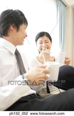 Mid adult couple holding cups of coffee and smiling View Large Photo Image Stock Image - Mid adult couple holding cups of coffee and smiling. Fotosearch