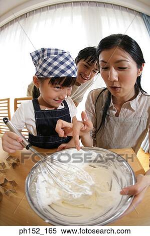 Stock Photography - Mid adult couple preparing cookie batter with their daughter. Fotosearch