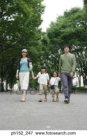 Stock Photo - Mid adult couple walking with their two daughters. Fotosearch