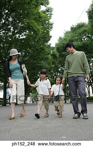 Stock Photo - Mid adult couple walking with their two daughters. Fotosearch