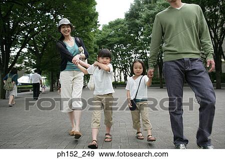 Stock Photo - Mid adult couple walking with their two daughters. Fotosearch