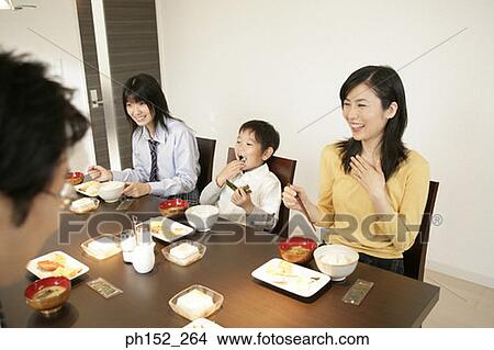 Picture - Mid adult couple with their son and daughter sitting at the dining table. Fotosearch