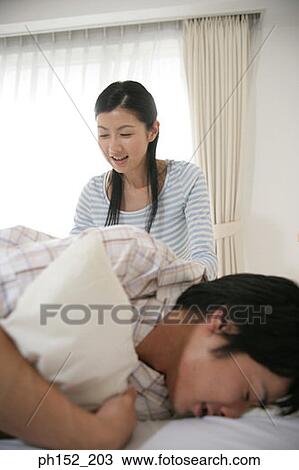Mid adult man sleeping on the bed with a mid adult woman sitting beside him View Large Photo Image Stock Image - Mid adult man sleeping on the bed with a mid adult woman sitting beside him. Fotosearch