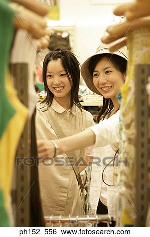 Stock Photograph - Mid adult woman and her daughter in a clothing store. Fotosearch