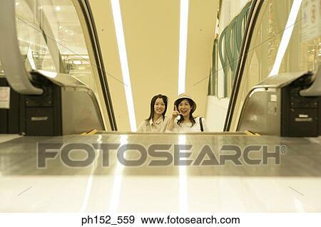 Stock Photo - Mid adult woman and her daughter on an escalator. Fotosearch