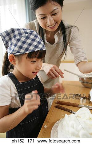 Mid adult woman and her daughter preparing food View Large Photo Image Stock Image - Mid adult woman and her daughter preparing food. Fotosearch
