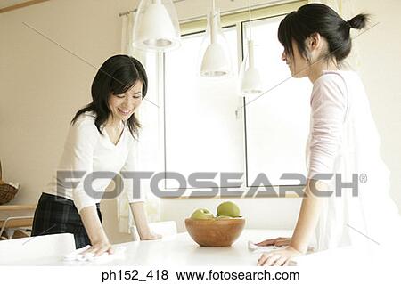 Mid adult woman and her daughter standing beside a table and talking to each other View Large Photo Image Stock Photo - Mid adult woman and her daughter standing beside a table and talking to each other. Fotosearch
