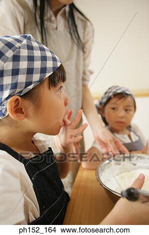 Picture - Mid adult woman and her two daughters making a cake. Fotosearch
