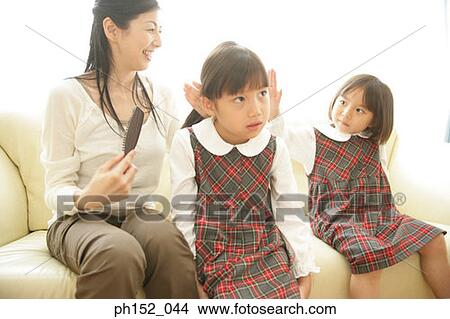 Mid adult woman brushing her daughter's hair View Large Photo Image Picture - Mid adult woman brushing her daughter's hair. Fotosearch