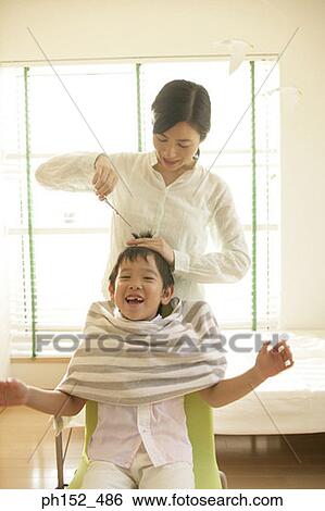 Stock Photograph - Mid adult woman cutting her son's hair. Fotosearch